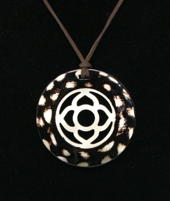 Close up of round horn pendant in dark horn with flower motif inner