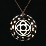 Close up of round horn pendant in dark horn with flower motif inner