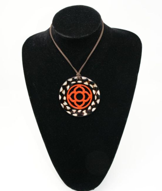 Close up of round horn pendant in dark horn with flower motif inner
