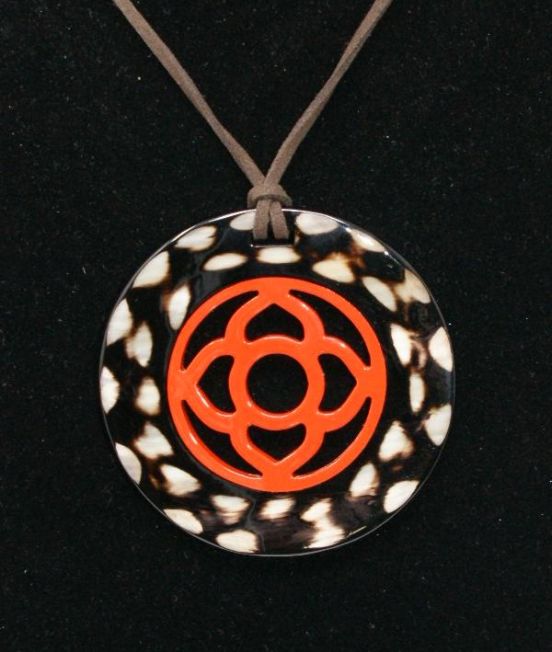Close up of round horn pendant in dark horn with flower motif inner
